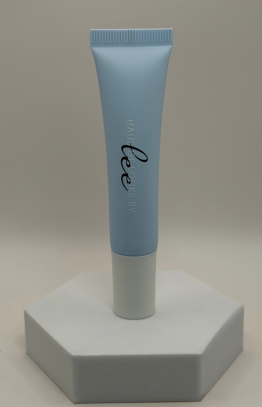 Blue tube of hair serum on a gray hexagonal stand against a beige background